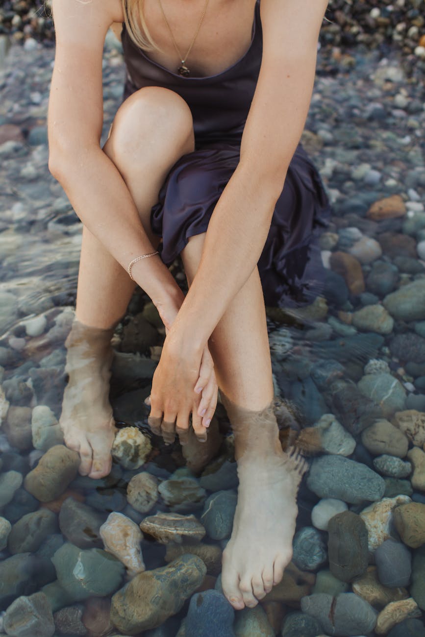 Image of a woman sitting in rocks and water on a beach